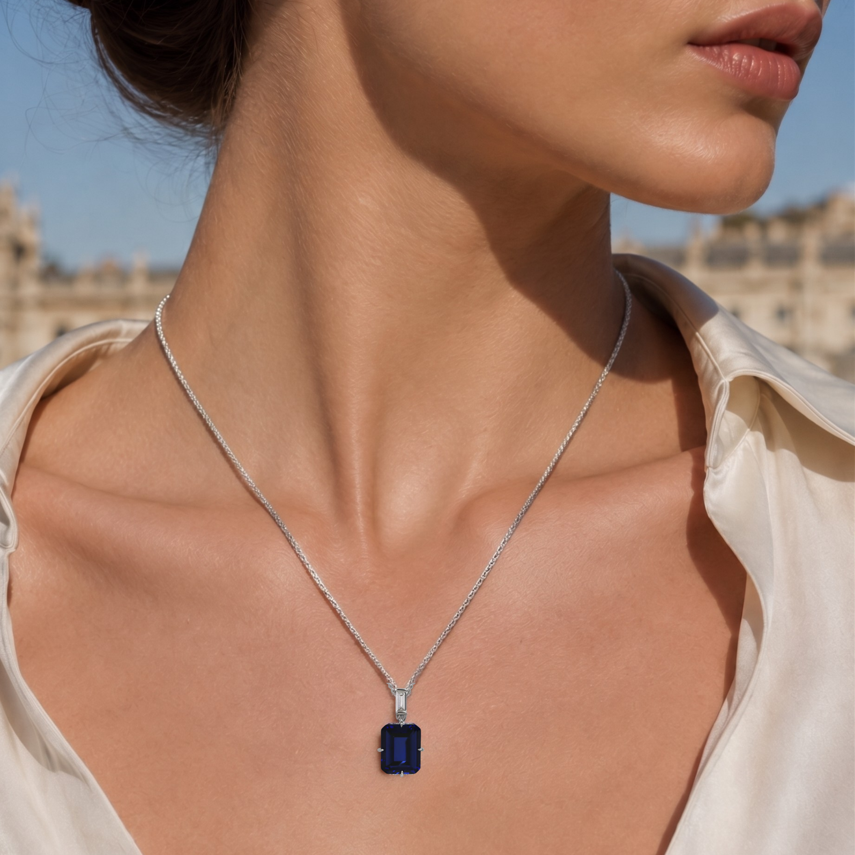 A model wears the London Bridge Blue Sapphire Pendant, featuring an emerald-cut sapphire on a silver chain.