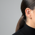 Woman's ear with Lark & Berry's Dreamcatcher Diamond Drop helix earring, a diamond stud, and a small gold hoop.