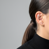 Woman's ear with Lark & Berry's Dreamcatcher Diamond Drop helix earring, a diamond stud, and a small gold hoop.