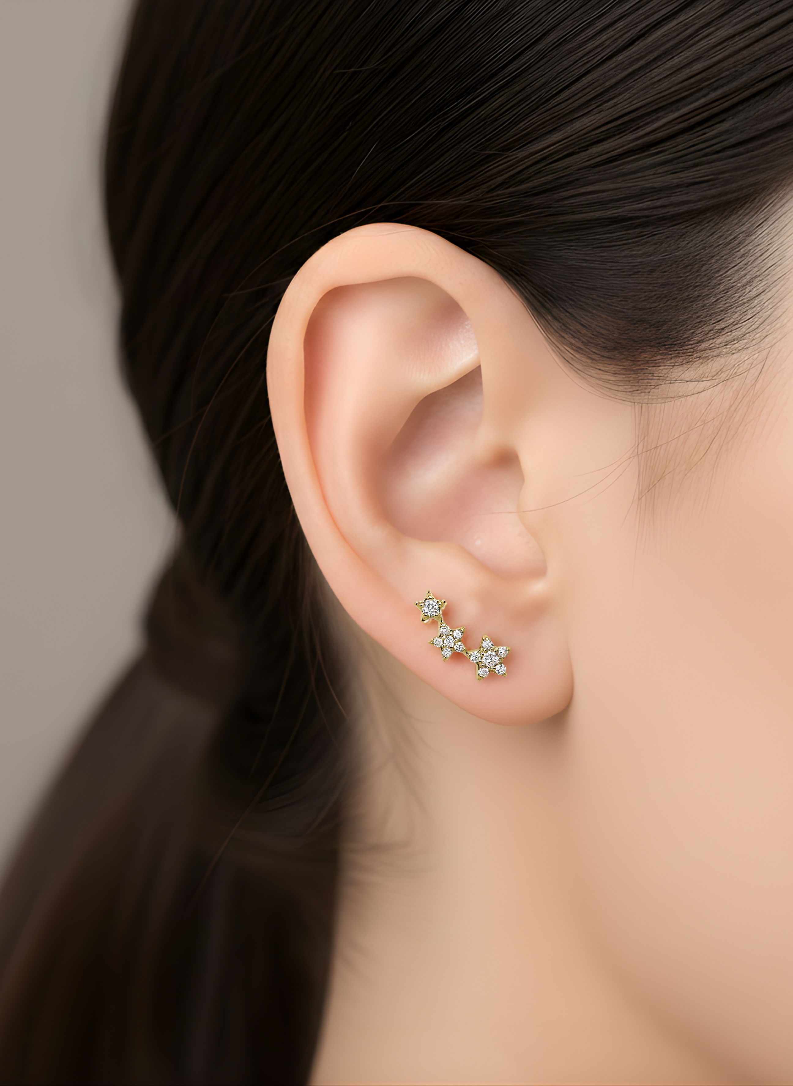 A model wears the 3-Star Diamond Stud earring, featuring three gold and diamond stars that climb up the earlobe.