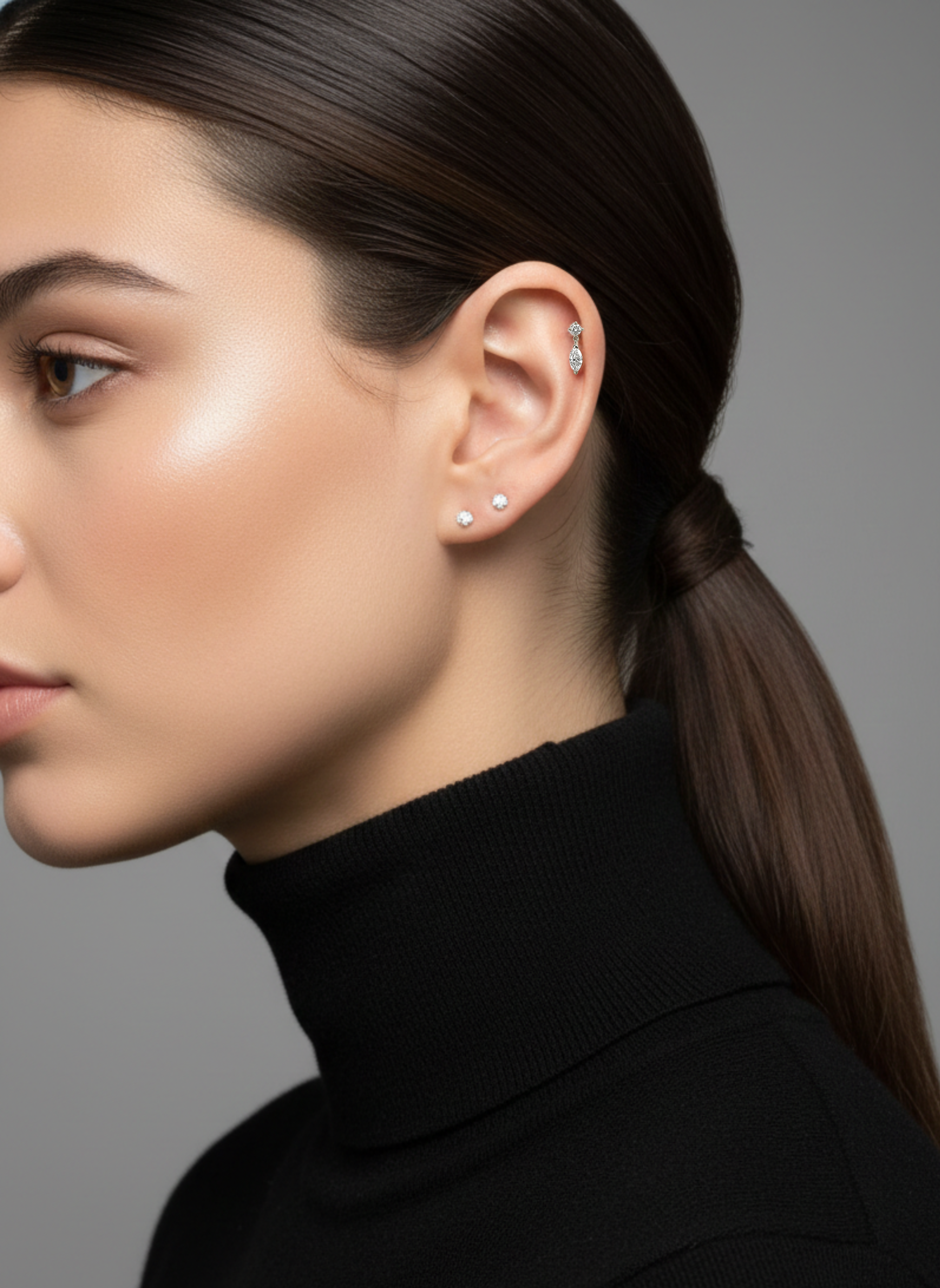 Profile of a model wearing the Marquise Double Diamond Drop Stud in her helix piercing, paired with two diamond studs.