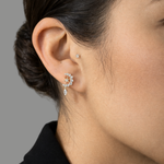 Model's ear wearing the gold Entwined Diamond Moon and Star Stud earring with a dangling diamond against a grey background.