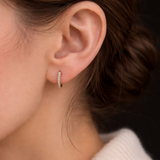 A woman wearing the Modernist Graduating Pave Hoop, a small gold earring with sparkling pave stones.