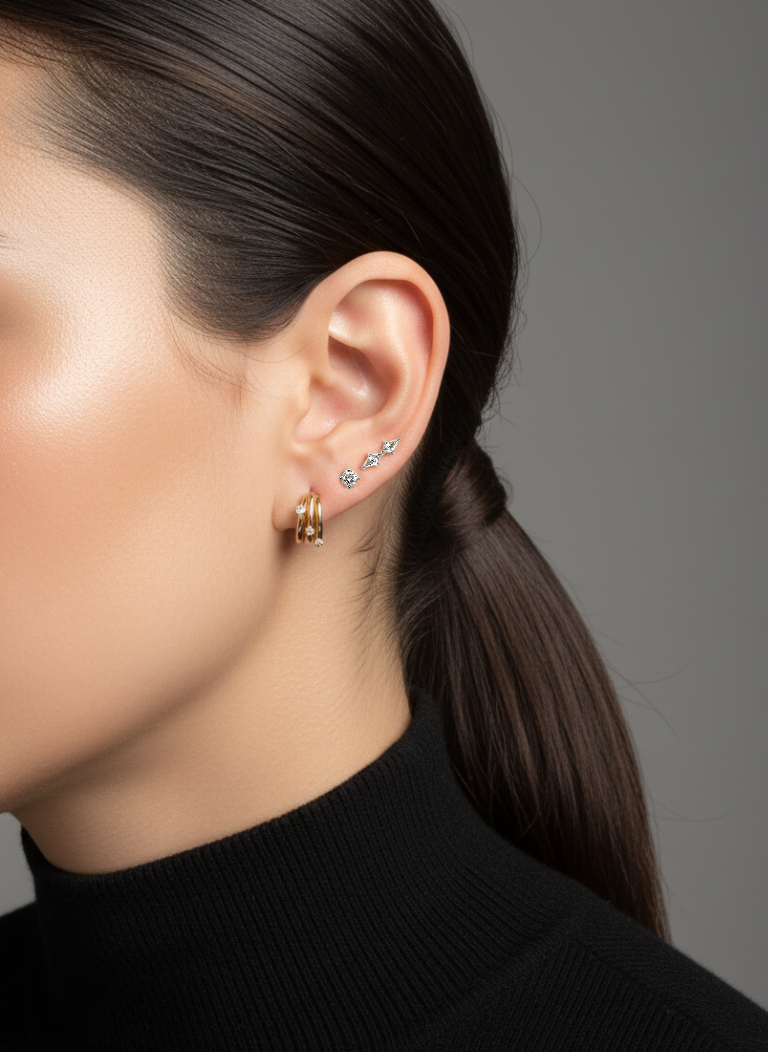 A close-up on a model's ear styled with gold diamond hoops and the Lark & Berry Double Diamond Kite Stud.