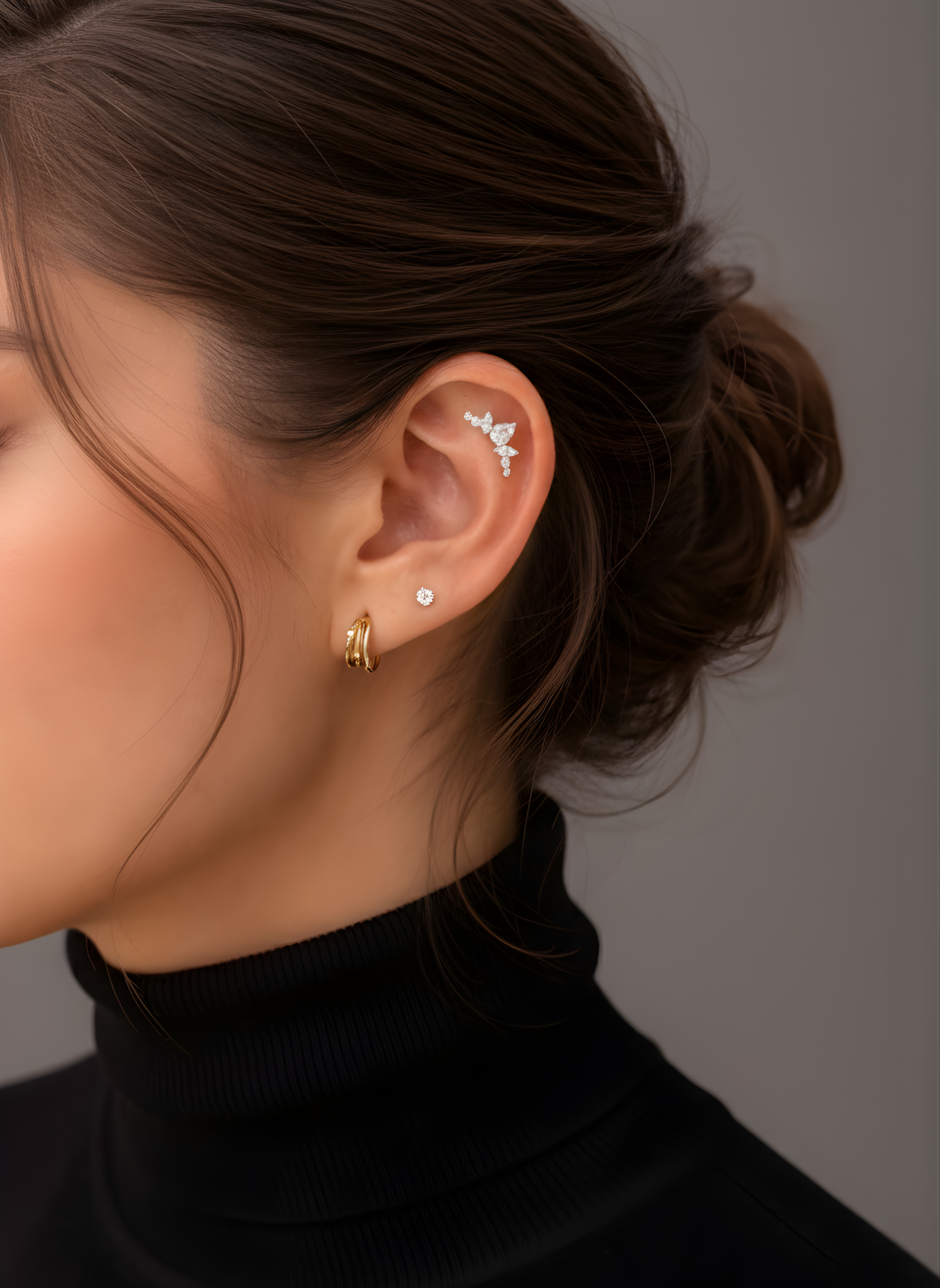 Model's ear styled with Lark & Berry's Crown Crawler diamond cartilage earring, a stud, and a gold hoop.