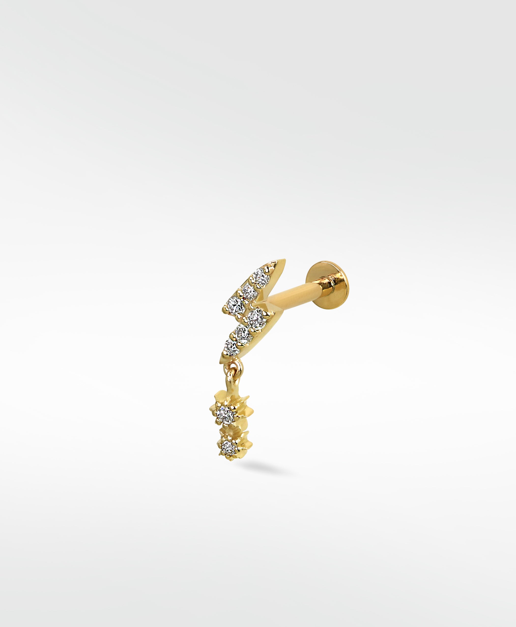 A gold lightning bolt labret stud earring paved with diamonds, featuring a dangling diamond drop charm on a white background.
