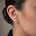 A model's ear with the Lark & Berry Lightening Bolt diamond drop earring in gold, featuring a starburst charm.