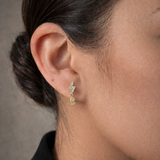 A model's ear with the Lark & Berry Lightening Bolt diamond drop earring in gold, featuring a starburst charm.