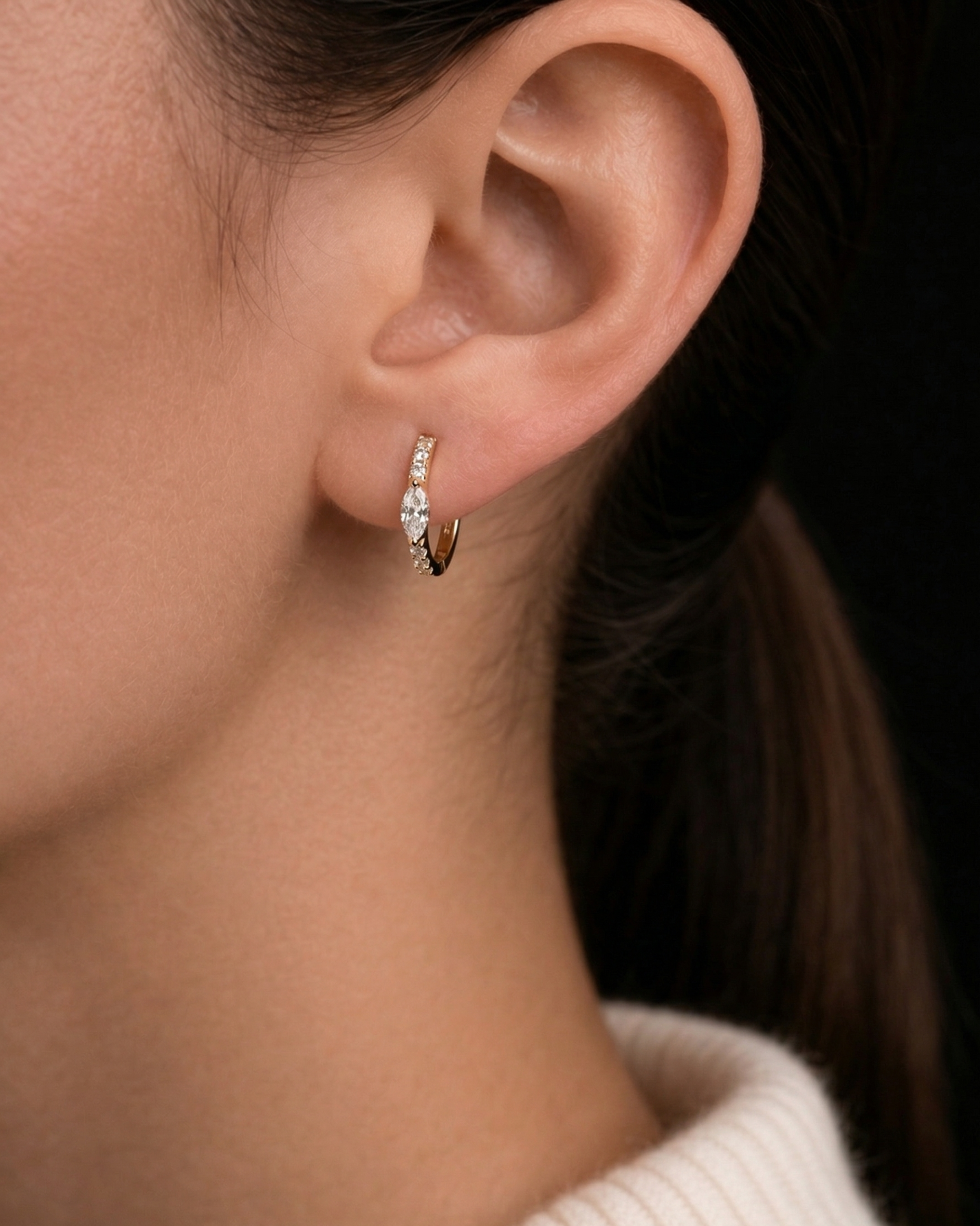 A model wears the gold Modernist Marquise Pave Hoop earring, featuring a central marquise diamond and pave details.